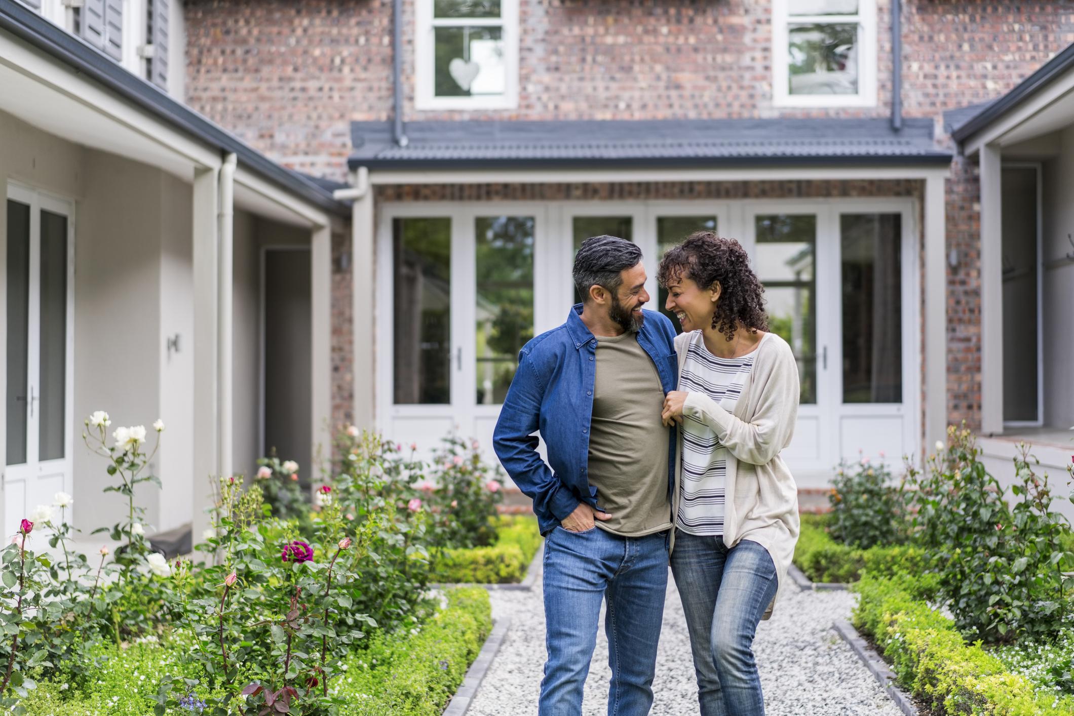 Smiling couple walking outside the front of their new home.