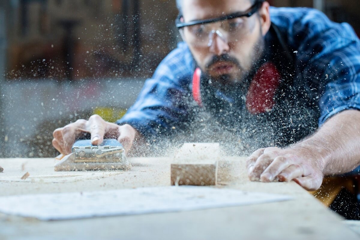 A home contractor sanding a piece of wood.