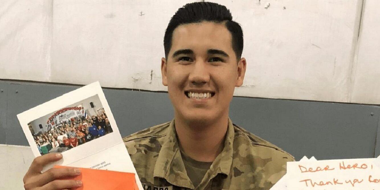 Soldier smiles while holding postcard that came with a care package.