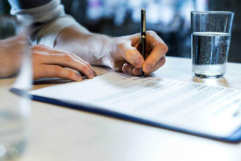 Close up of a man's hands signing a document.